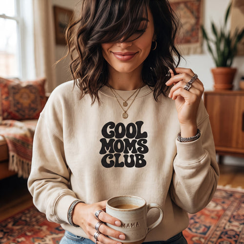 ChalkboardxChaos beige crewneck sweatshirt with black retro bubble lettering reading Cool Moms Club on a woman