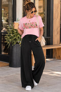 ChalkboardxChaos black wide-leg lounge pants with drawstring waist worn by a woman with a pink graphic t-shirt