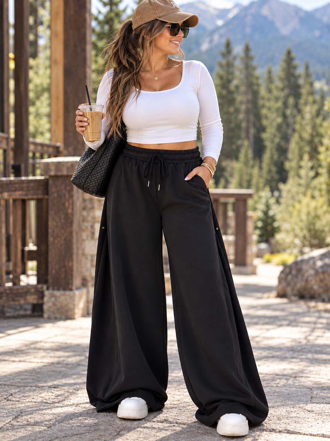 ChalkboardxChaos black wide-leg lounge pants with drawstring waist worn by a woman with a white top and baseball cap