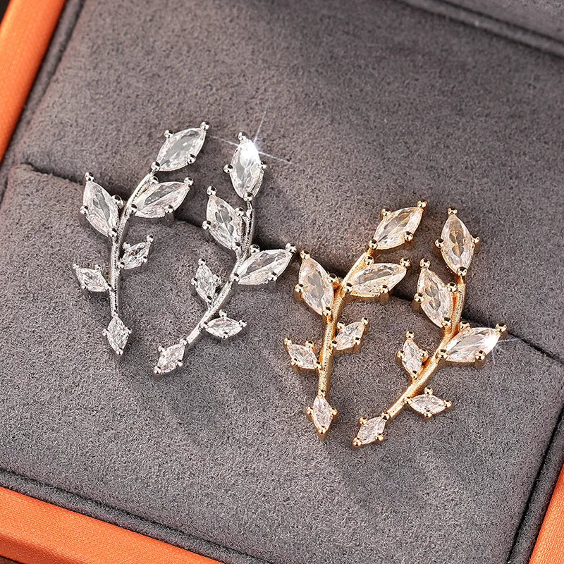 ChalkboardxChaos silver and gold-tone crystal leaf branch earrings with marquise-cut stones in a jewelry box.