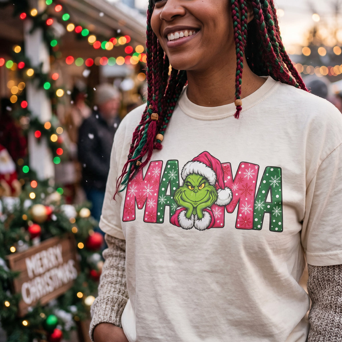 ChalkboardxChaos cream graphic tee featuring Grinch Mama text with pink and green snowflake patterns and Santa hat