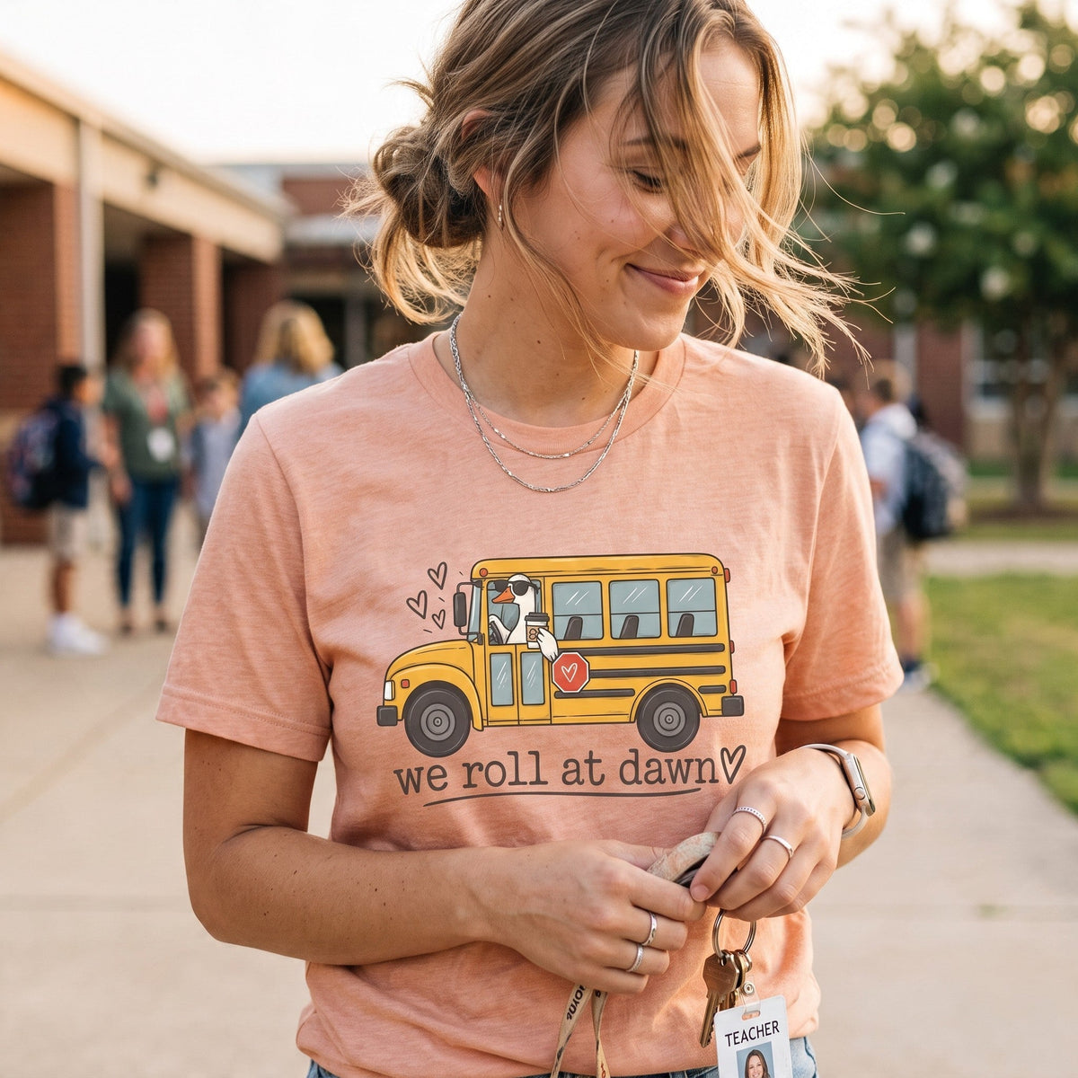 ChalkboardxChaos mauve teacher t-shirt featuring a yellow school bus graphic with the text We Roll at Dawn