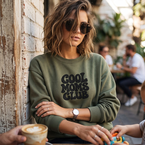 ChalkboardxChaos olive green crewneck sweatshirt with black retro bubble lettering reading Cool Moms Club on a woman