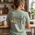 ChalkboardxChaos sage green graphic tee with Motherhood Is Kingdom Work text and botanical floral print on the back