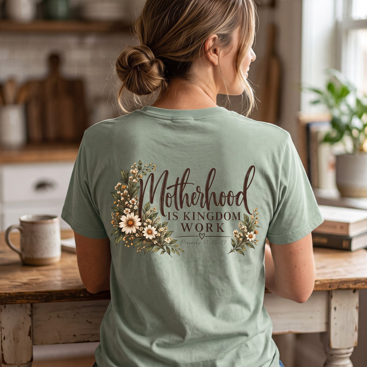 ChalkboardxChaos sage green graphic tee with Motherhood Is Kingdom Work text and botanical floral print on the back